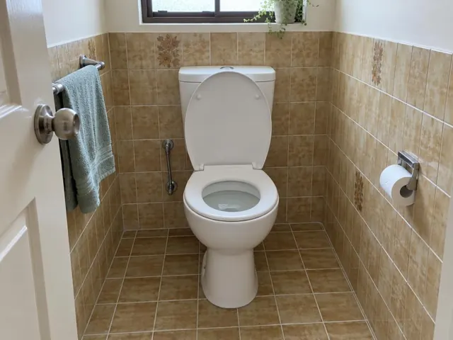 Clean white toilet in a tiled bathroom with a towel rail and window in Seaforth